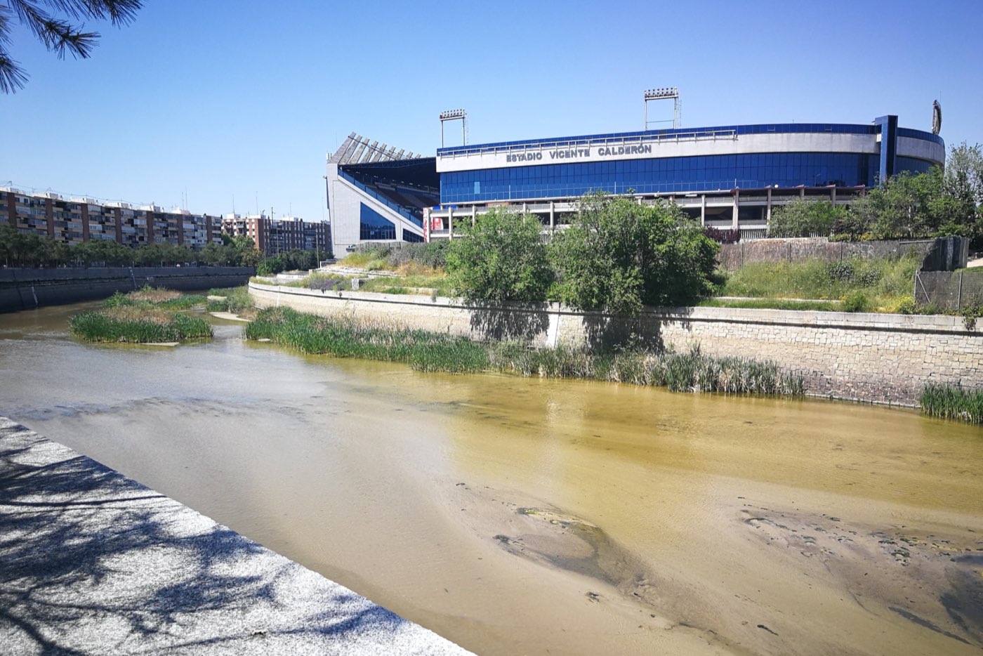 Fachada azul del Vicente Calderón con su nombre en grande, vista desde la otra orilla del Manzanares