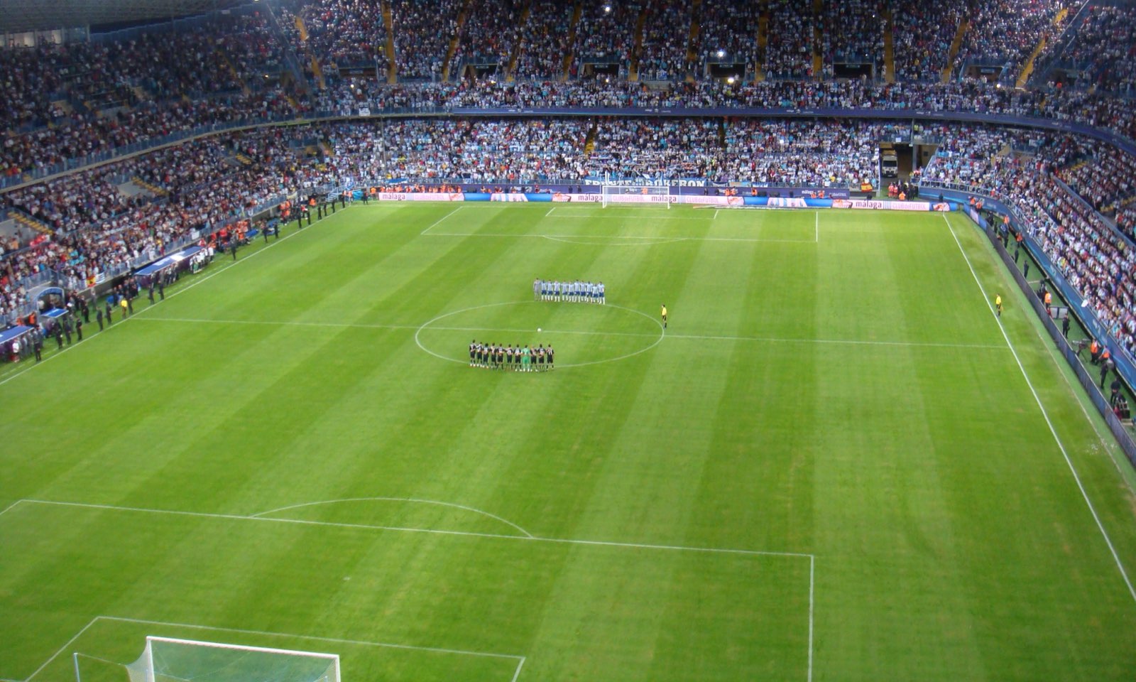 La Rosaleda desde lo alto de un fondo, con las gradas llenas y los equipos formados antes de empezar
